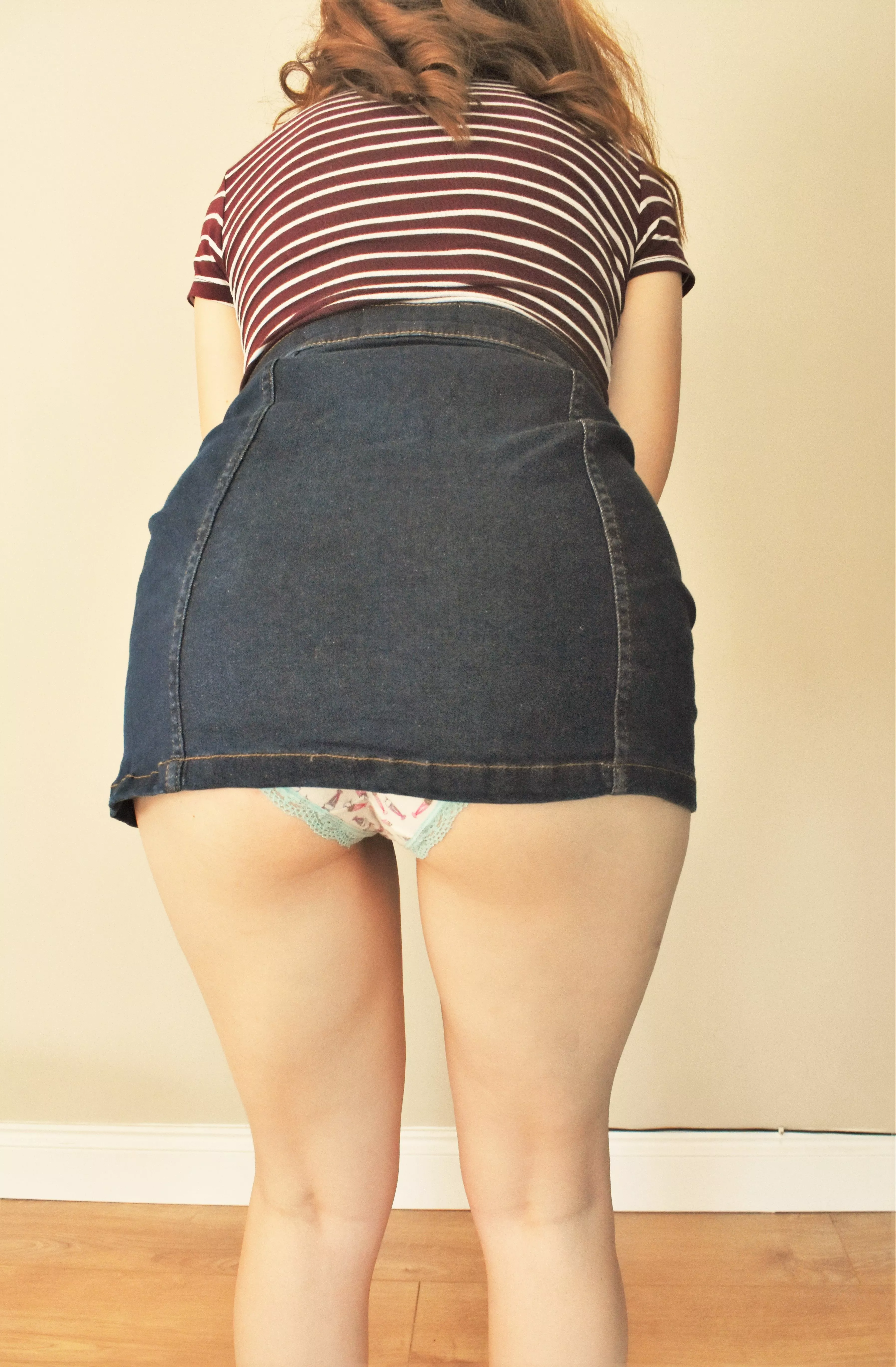 Bent over in a denim skirt