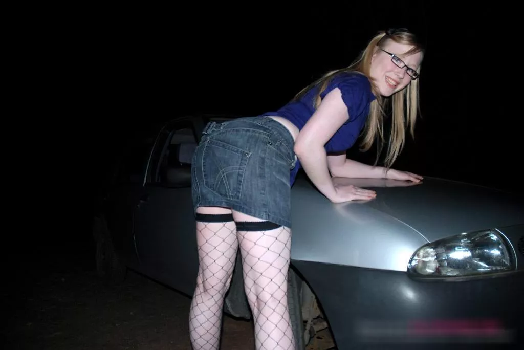 Satine Spark bent over a car in the dark