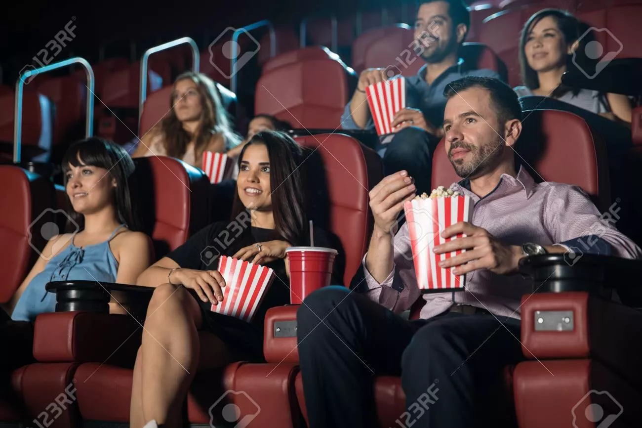 Small audience of adults watching a movie and eating snacks