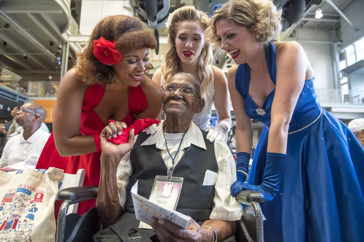 Victory Belles give World War II veteran Lawrence Brooks a birthday card and kiss for his 110th birthday celebration at the National WWII Museum